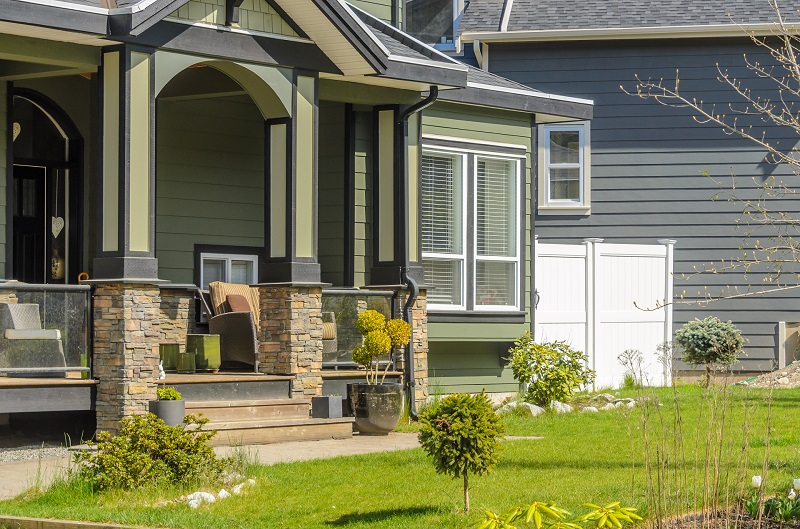 nice home with green exterior and stone porch